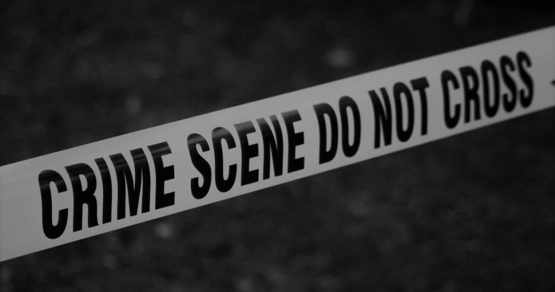 A black and white image showing a crime scene tape, marked with "CRIME SCENE DO NOT CROSS" in bold letters.